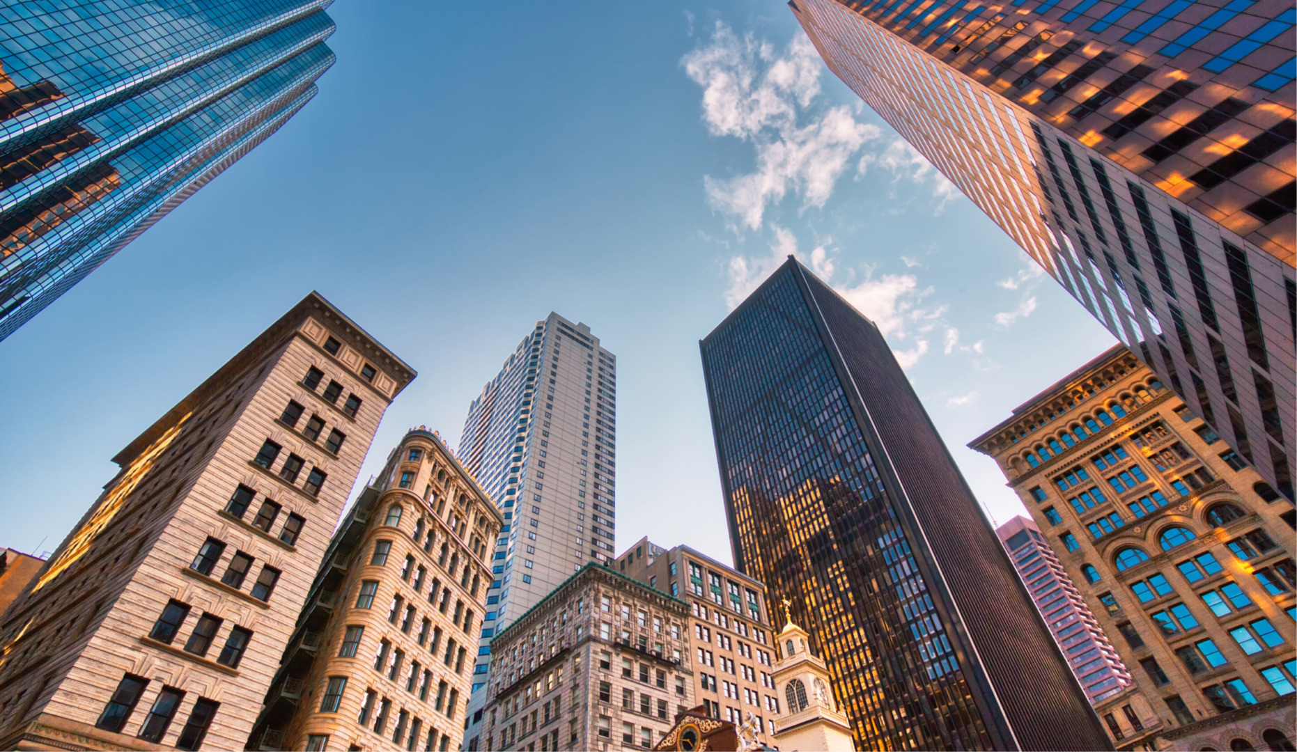 Cityscape view with tall skyscrapers under a clear blue sky, showcasing a mix of modern and historic architecture.